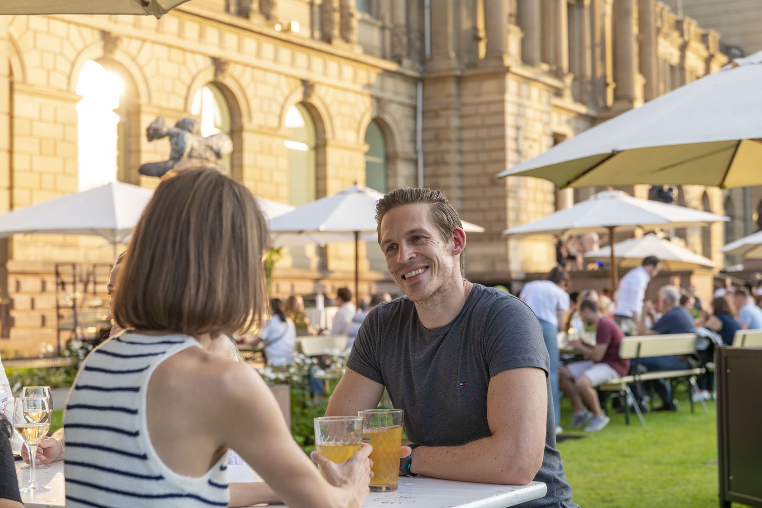 Personen sitzen mit Getränken vor Museumsgebäude in Frankfurt