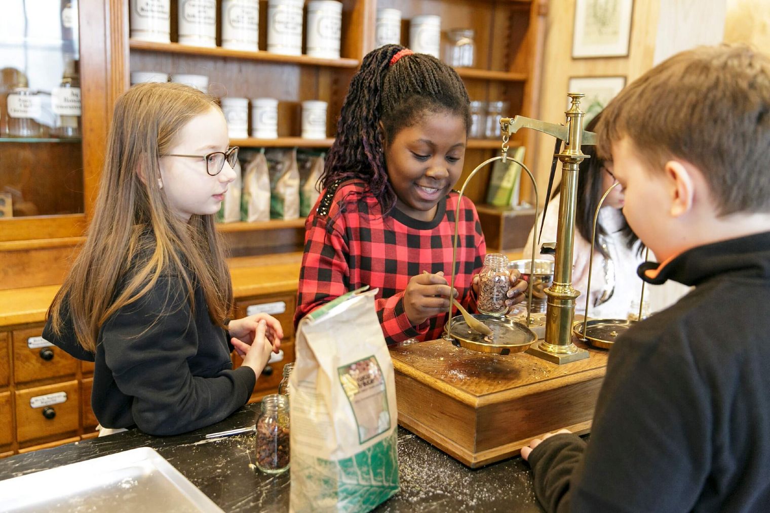 Children play in a reconstructed old pharmacy and weigh something. 
