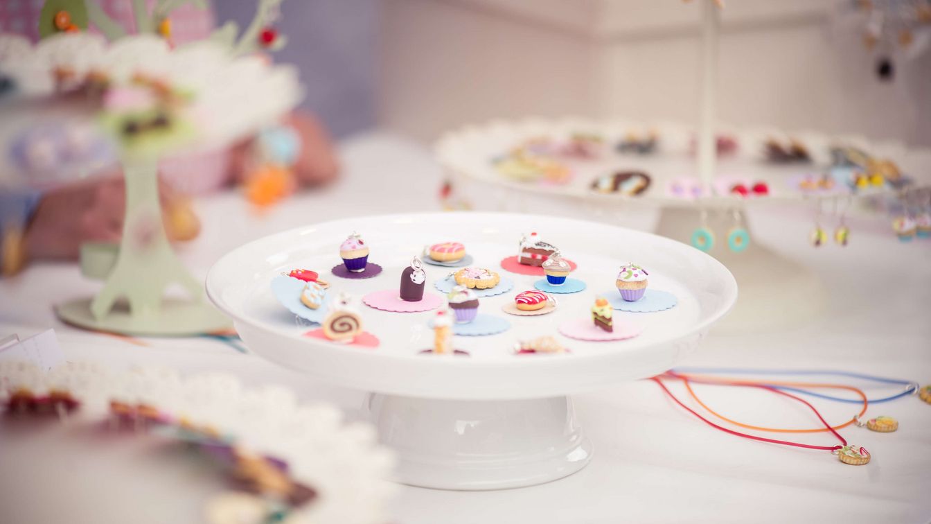 Miniatur‑Schmuck in Tortenform an Marktstand