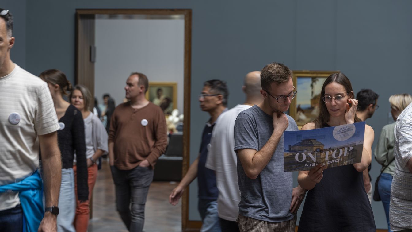 Besucher lesen Plan in Museumssaal mit Gemälden