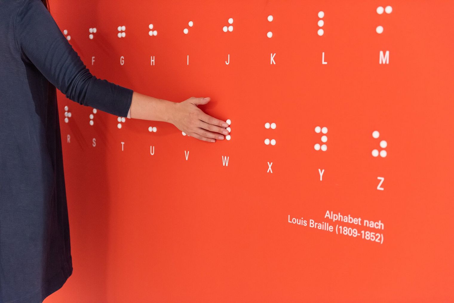 Ein Hand auf einer Wand mit dem Braille Schrift Alphabet