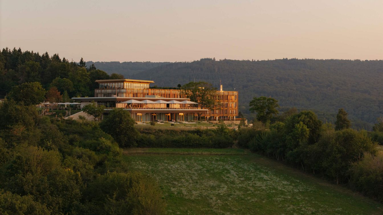 Modernes Gebäude auf Hügel mit Terrasse und Waldlandschaft