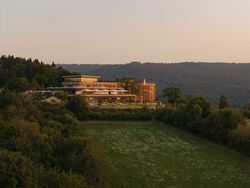 Modernes Gebäude auf Hügel mit Terrasse und Waldlandschaft